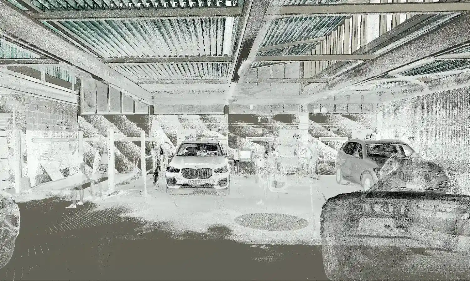 Interior 3D point cloud laser scan data of the UK police complex garage, capturing structural columns and parked police vehicles.